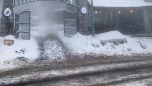 A snow-covered railway station with a bridge, a sign indicating a no parking zone, and a building with a snow-covered roof. - GreyVillas (Murree)