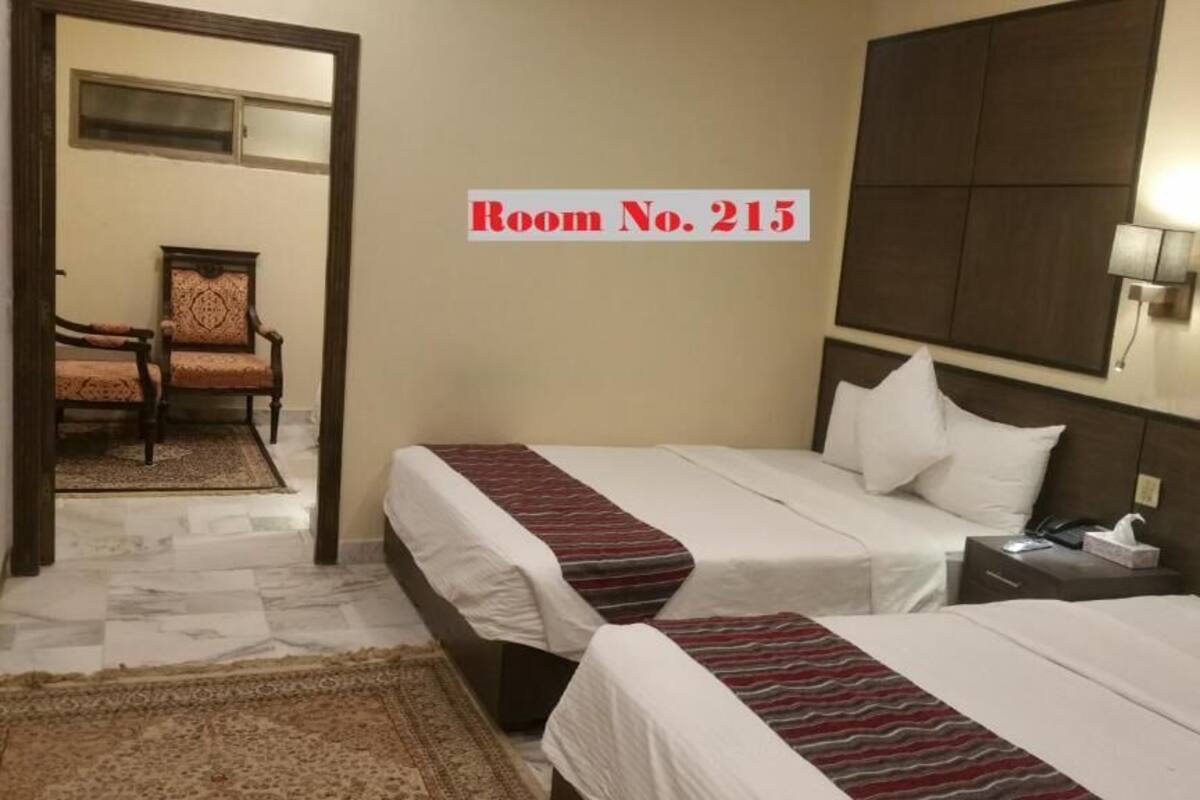 Una habitación de hotel con dos camas, una mesita de noche, una lámpara y una silla.