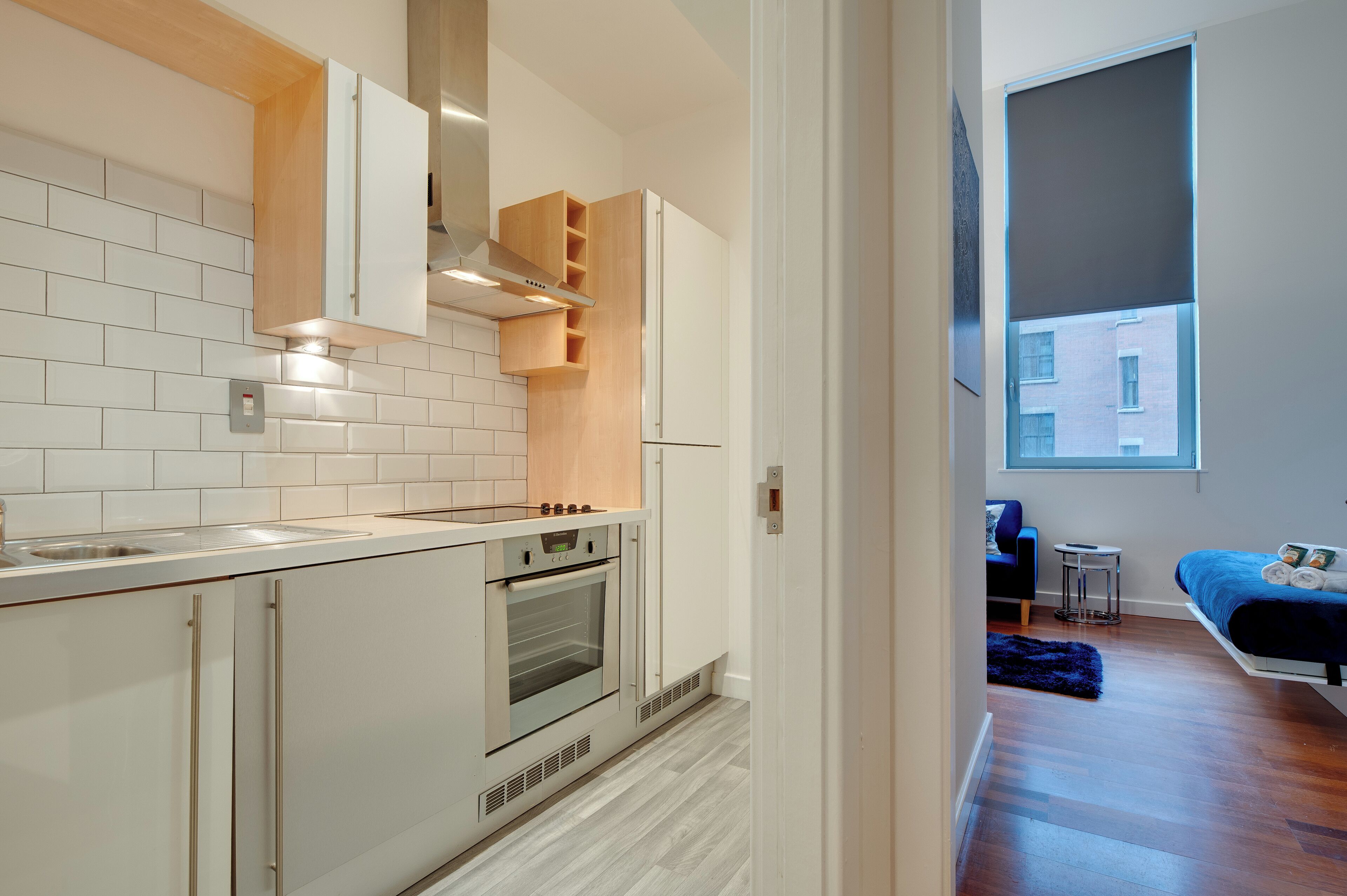Een moderne keuken met witte kasten, een ingebouwde oven en een raam met uitzicht op een stadsbeeld.