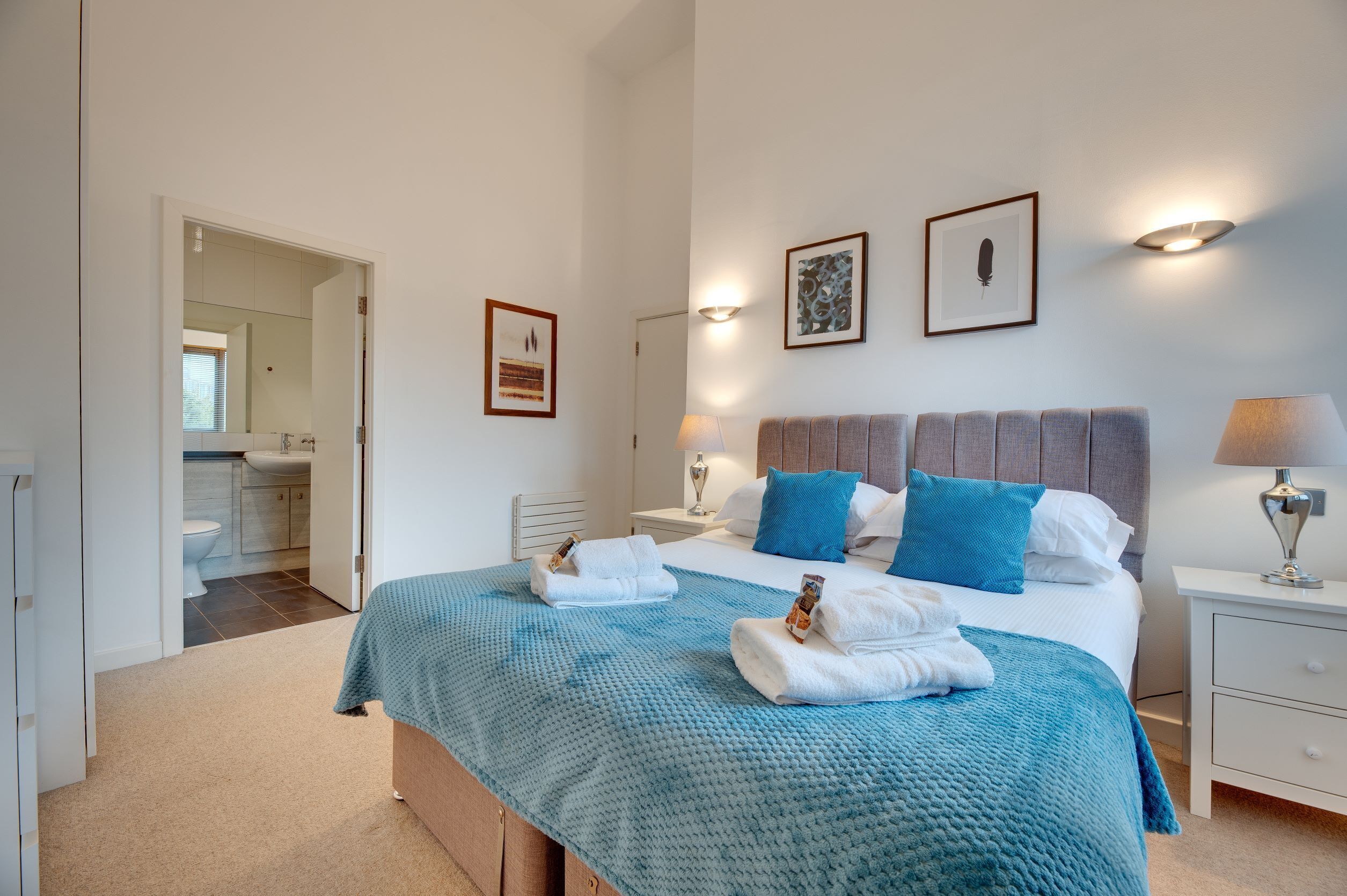 A bedroom with a bed, bedside tables, and a bathroom visible through an open door.