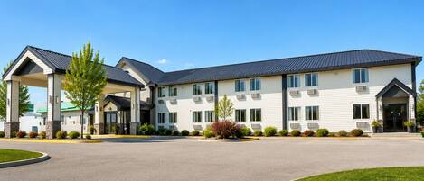 A multi-story hotel with a covered entrance, air conditioning units, and a parking lot.