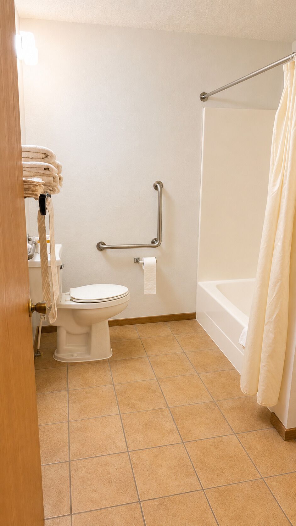 Un baño con inodoro, barra de apoyo, bañera y cortina de ducha.
