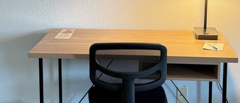A tidy desk with a chair, a framed quote on the wall, and a lamp.