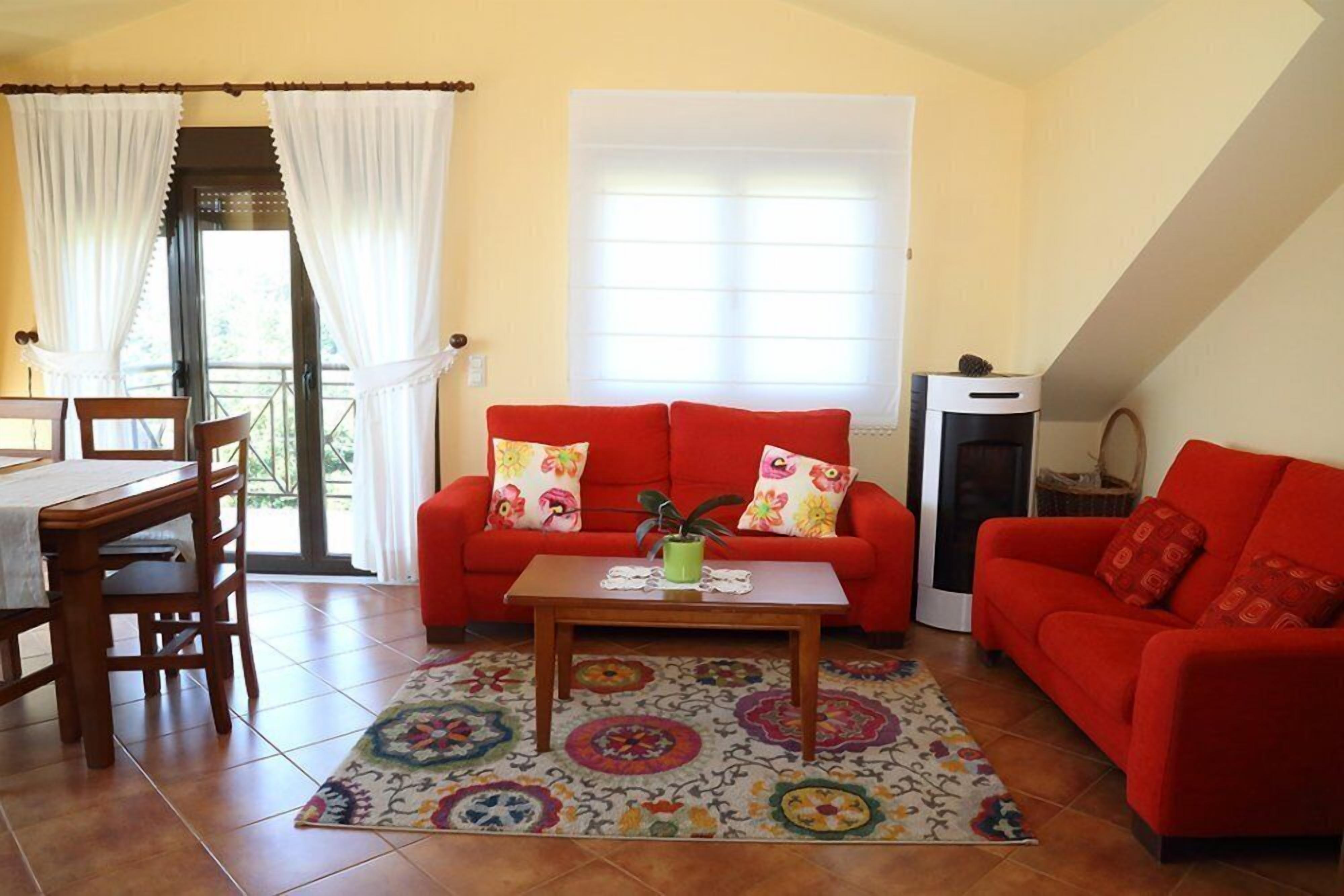 A living room with a red sofa, a wooden coffee table, and a patterned rug.