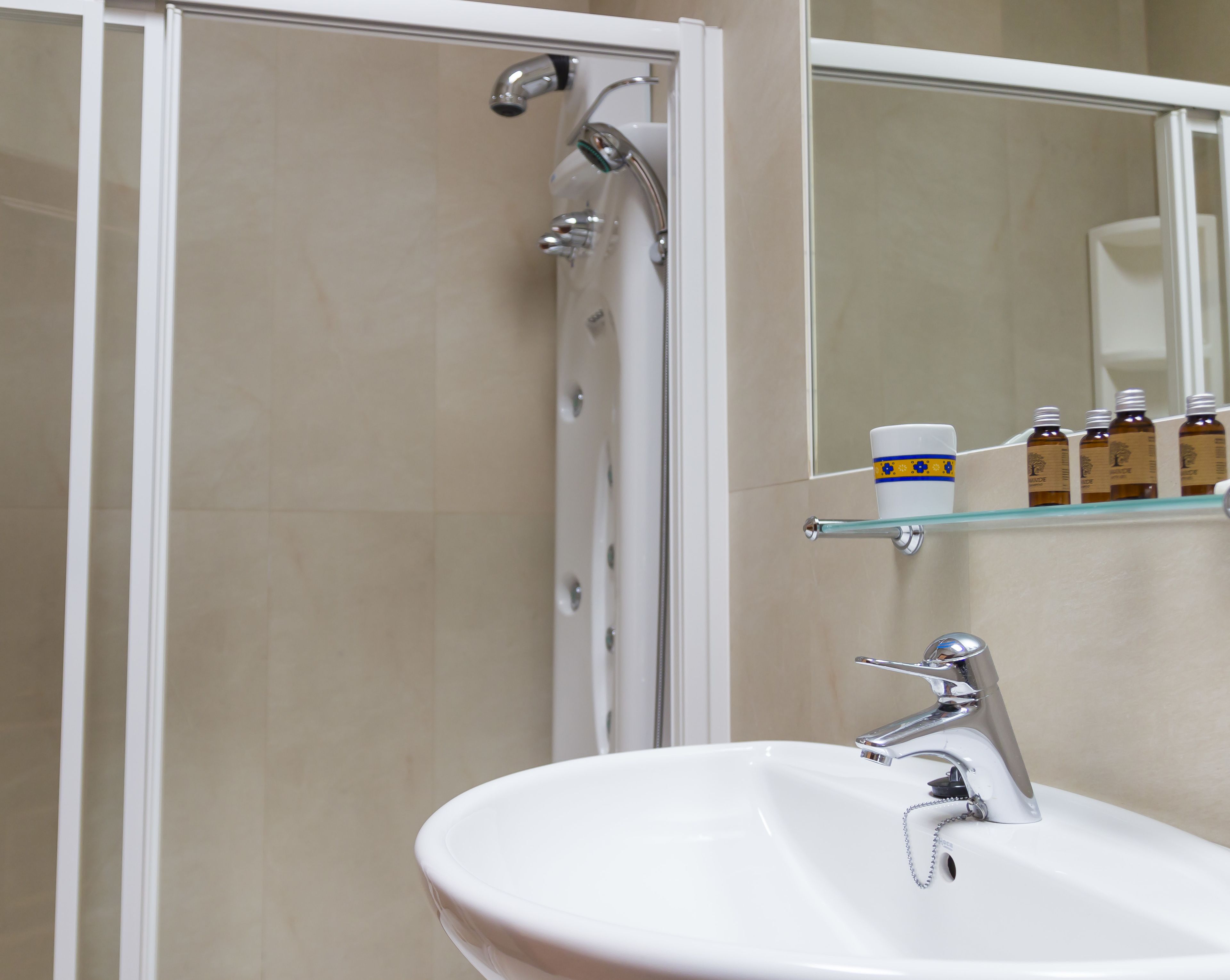 A bathroom with a white sink, a mirror, and a shower enclosure.