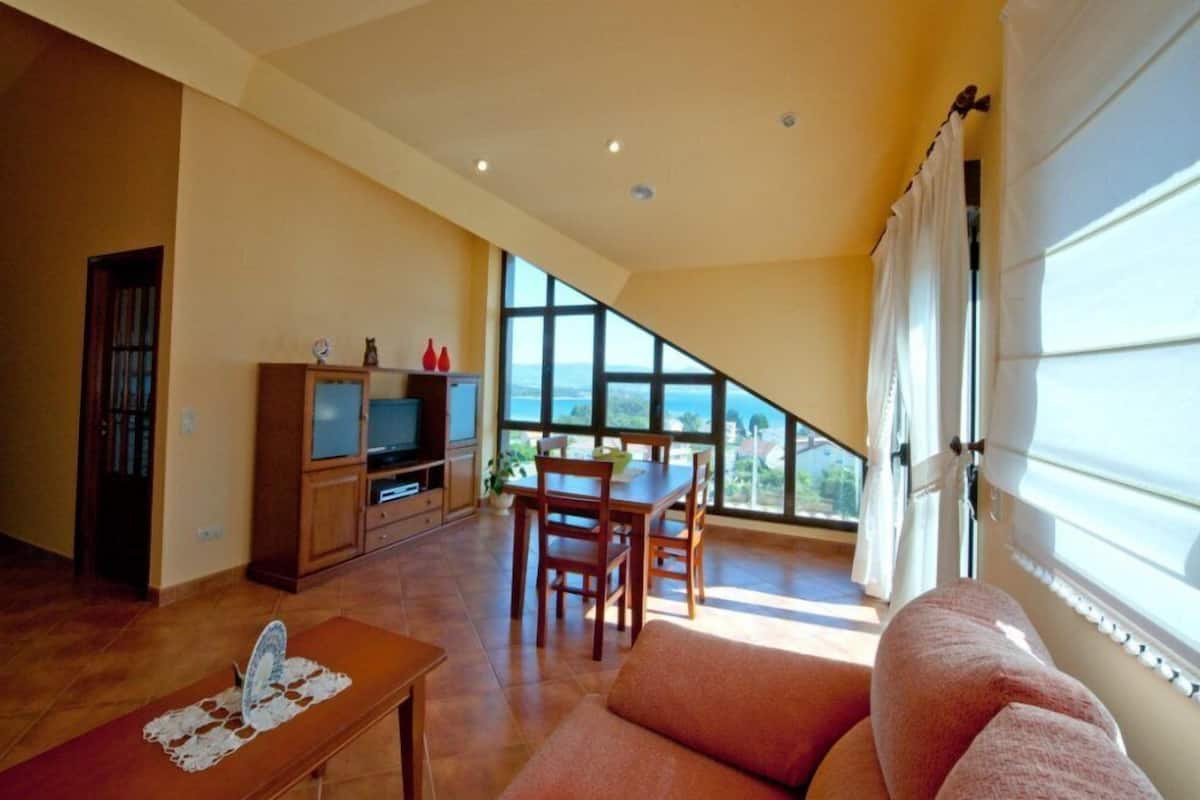 Amplia sala de estar con mesa de comedor, sofá y televisor.
