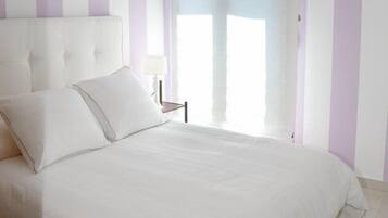 Un dormitorio con una cama grande, una mesita de noche y un ventanal con cortinas.