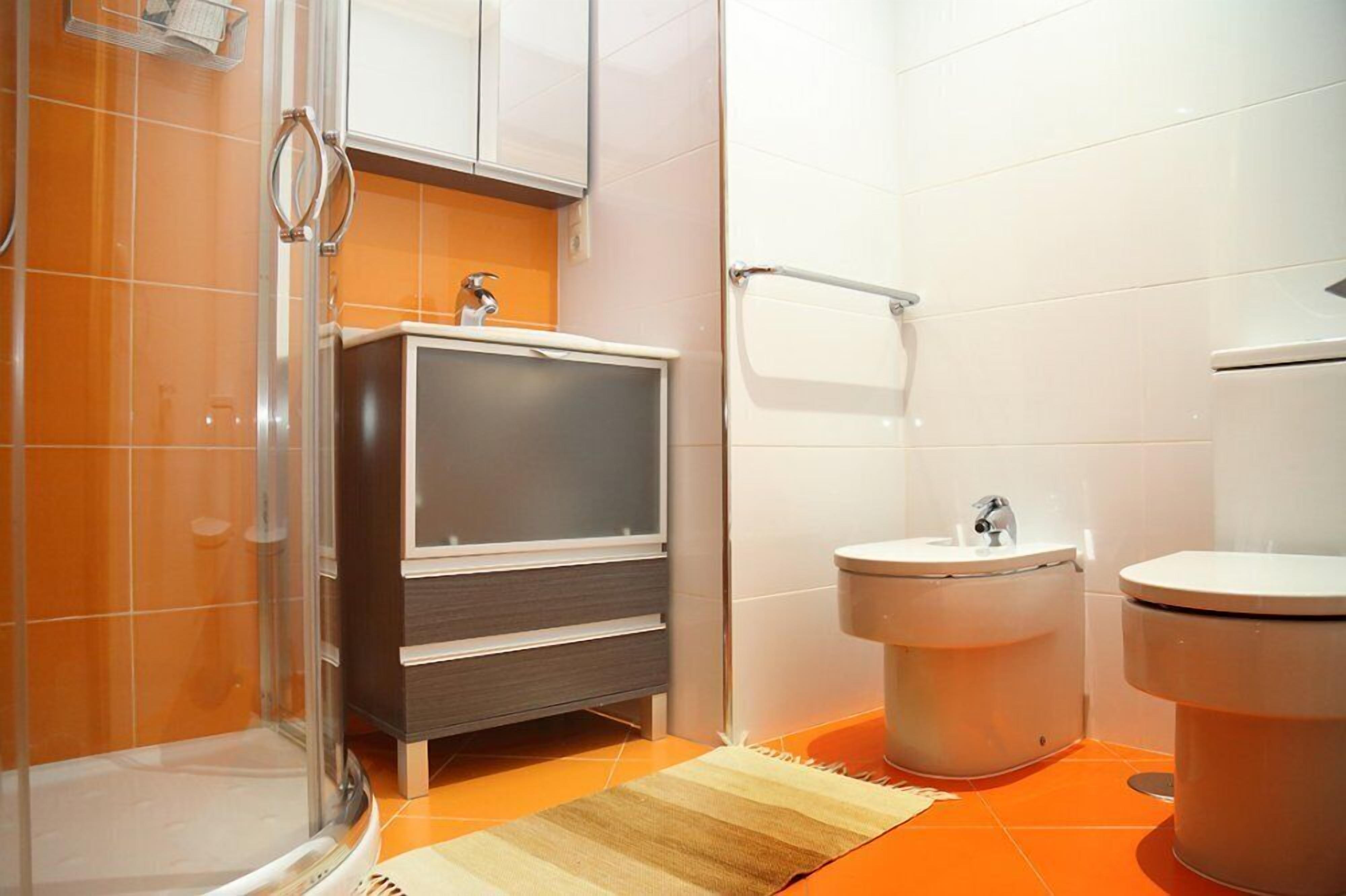 A bathroom with a shower, a vanity with a mirror, a bidet, and a toilet.