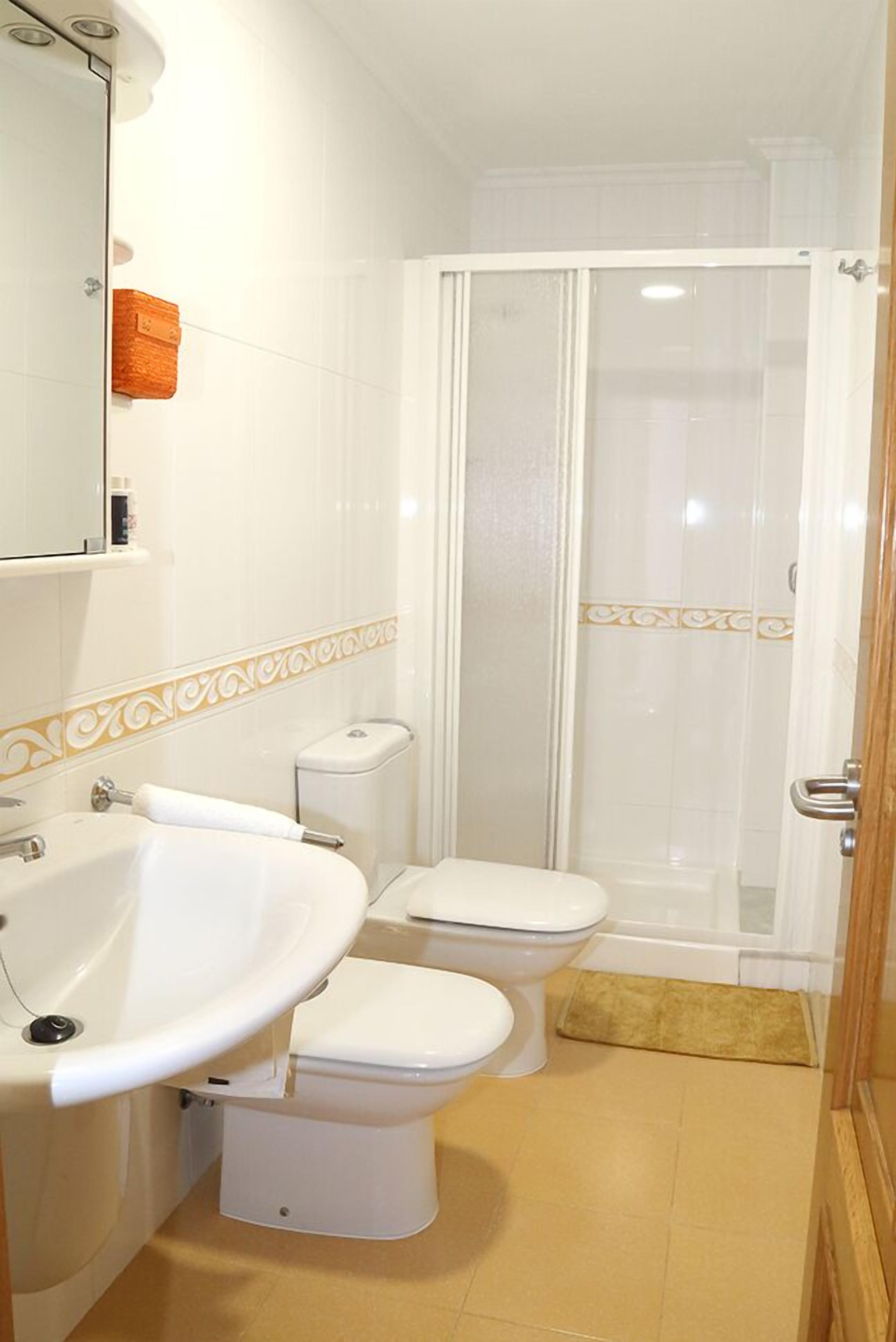 Un baño con lavamanos, inodoro y zona de ducha.