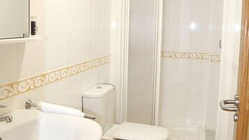Un baño con lavamanos, inodoro y zona de ducha.