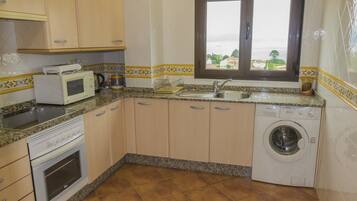 Una cocina equipada con microondas, horno, lavaplatos y lavadora.