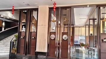 A hotel lobby with a curved staircase, wooden paneling, and a glass partition.