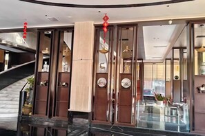A hotel lobby with a curved staircase, wooden paneling, and a glass partition. - Jin Li Hua Grand Hotel (Shaodong)