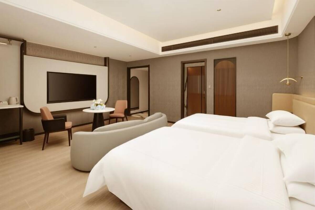 Une chambre d’hôtel moderne équipée d’un grand lit, d’une télévision, d’un coin salon et d’un bureau.