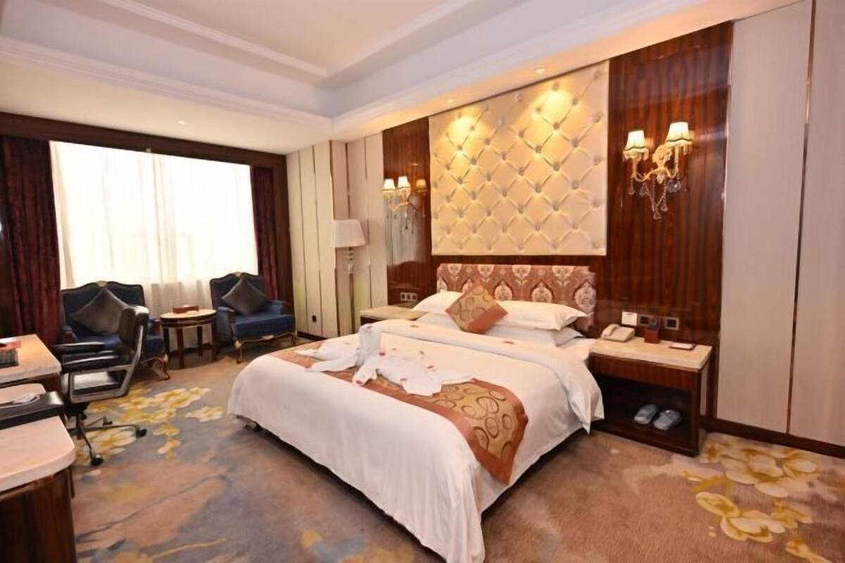 Une chambre d’hôtel avec un grand lit, deux tables de chevet, un bureau et une chaise.