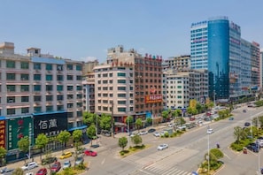 A cityscape with multiple buildings, a clear sky, and a busy street with cars. - Jin Li Hua Grand Hotel (Shaodong)