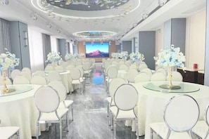 A conference room with round tables, chairs, and a large screen at the front. - Jin Li Hua Grand Hotel (Shaodong)