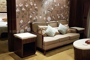 A living room with a sofa, two side tables, and a round coffee table. - Jin Li Hua Grand Hotel (Shaodong)