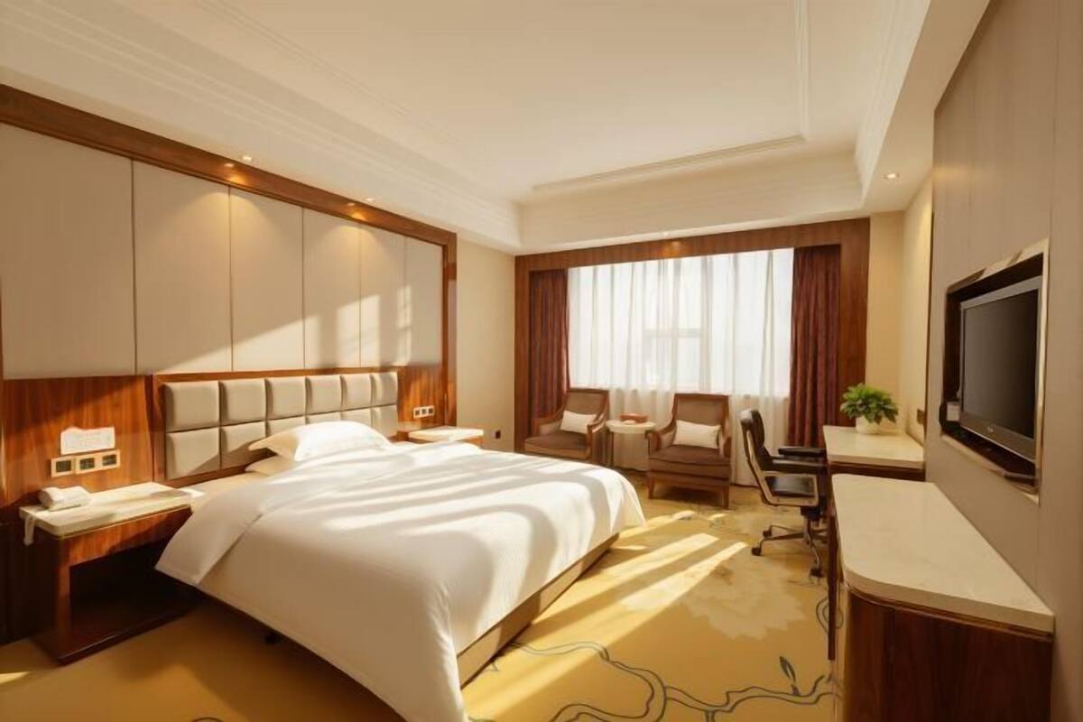 Une chambre d’hôtel avec un grand lit, un bureau, une chaise et un téléviseur.