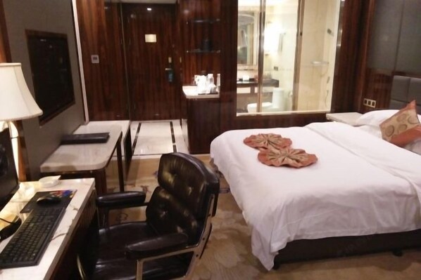 A hotel room with a bed, a desk with a computer, a chair, and a mirror. - Jin Li Hua Grand Hotel (Shaodong)