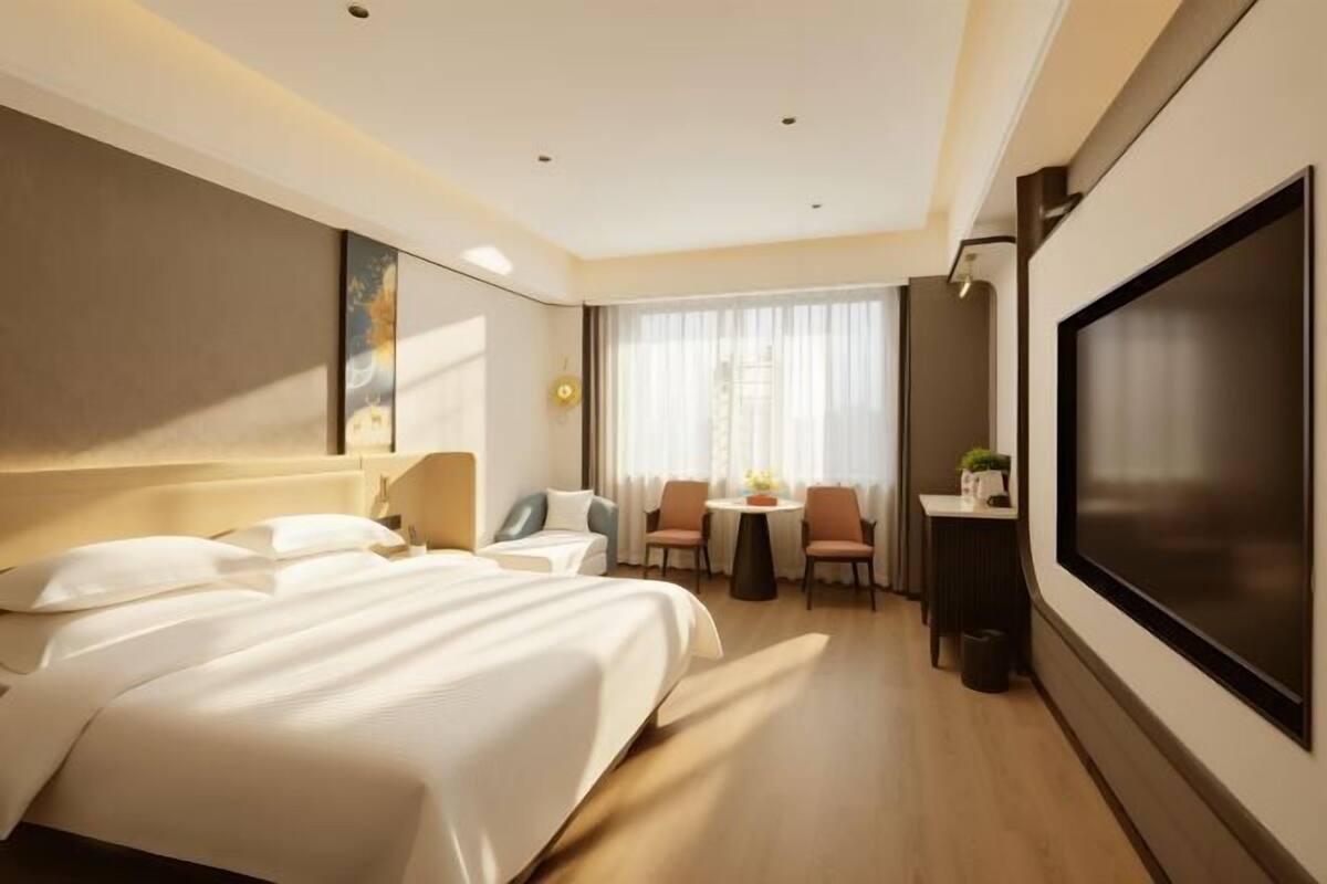 Une chambre d’hôtel moderne dotée d’un grand lit, d’un bureau, d’une télévision et d’un coin salon avec une table et des chaises.