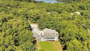 Uma casa grande rodeada por uma floresta densa e um lago.