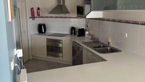 A kitchen with a microwave, stove, sink, and a small window above the microwave. - Quelle Vue HUSKISSON - Means What a View in French - The only place to stay (Huskisson)