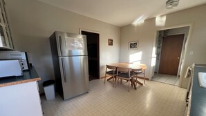Una cucina compatta con frigorifero, microonde e tavolo con sedie.
