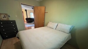 Una camera da letto con un letto, una cassettiera e una porta che dà su un'altra stanza.