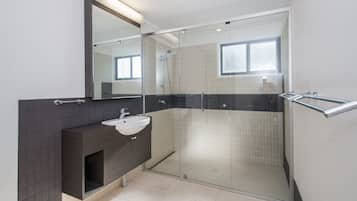 A modern bathroom with a glass-enclosed shower, a white sink, and a dark-toned vanity.