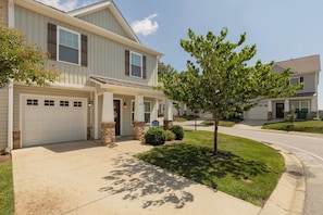 A two-story house with a garage, a covered porch, and a well-maintained lawn.