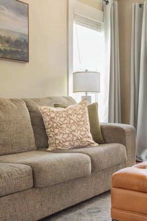 A living room with a sofa, a lamp, and a painting on the wall.