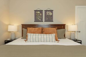 A neatly made bed with two pillows, a headboard, and two bedside lamps.
