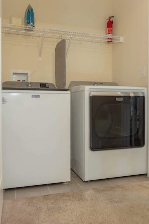 A laundry room with two Maytag washing machines, a fire extinguisher, and a drying rack.