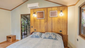 A bedroom with a large bed, wooden panel walls, two wall-mounted lights, and a ceiling fan.