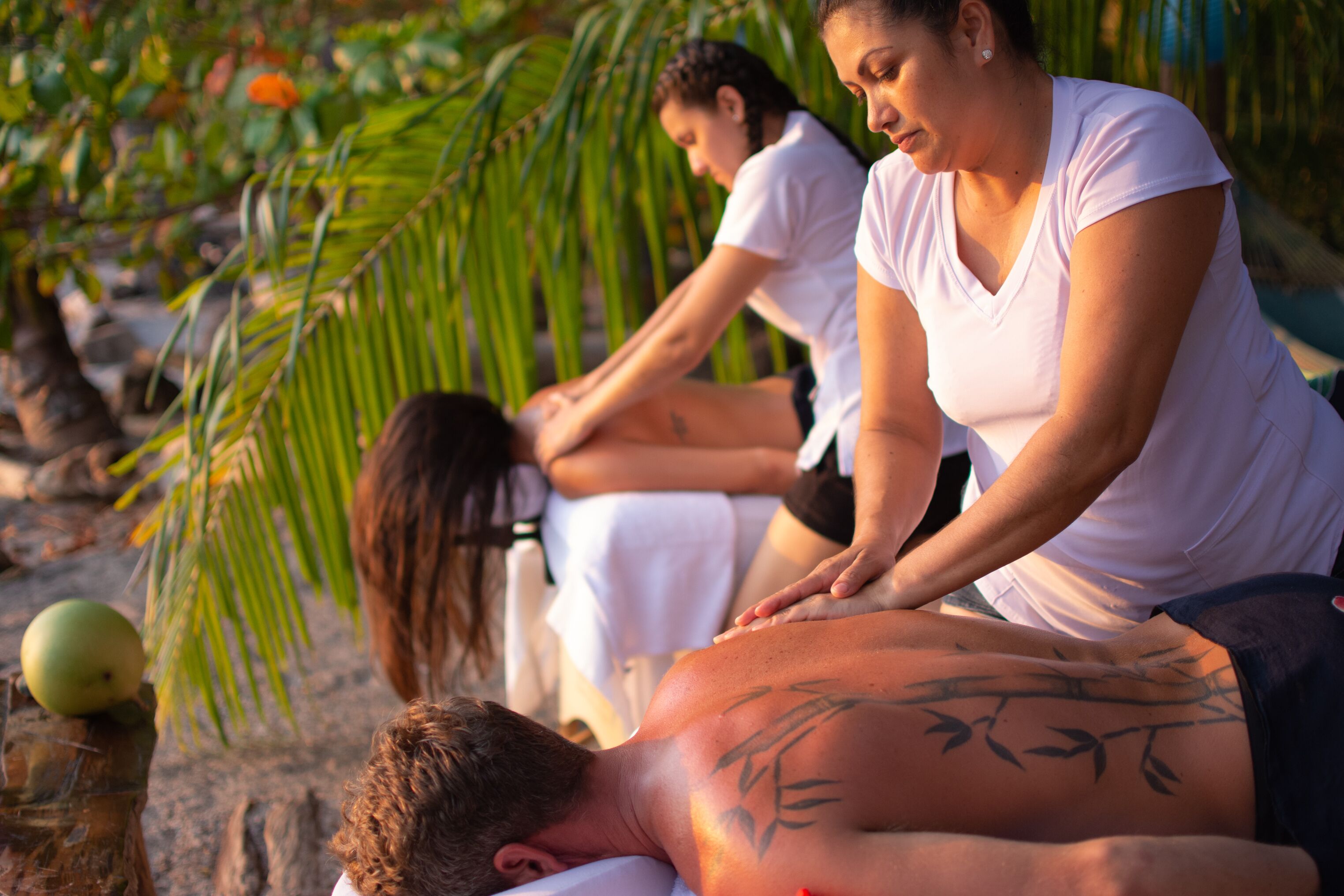 Een massagebehandeling in een tropische omgeving, met palmbomen en een ontspannen sfeer.