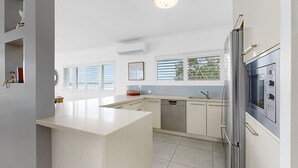 Uma cozinha moderna com uma ilha central, eletrodomésticos embutidos e grandes janelas.