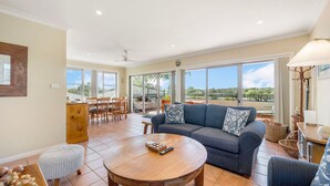Un vaste espace de vie comprenant un grand canapé, une table ronde en bois et un balcon offrant une vue sur l’extérieur.