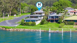 Une propriété située au bord de l’eau, avec une grande maison dotée d’un balcon et d’un garage.