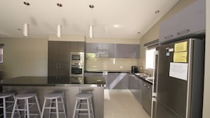 Enjoy cooking and dining in this sleek kitchen with a large window, stainless steel appliances, and a functional island with bar stools.