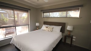 Comfortable bedroom with a large bed, bedside tables, and a ceiling fan.