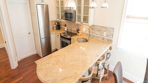 A kitchen with granite countertops, stainless steel appliances, and pendant lighting.