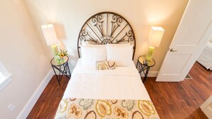 A neatly made bed with a patterned bedspread, two bedside tables with lamps, and a wall-mounted light fixture.