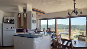 Une cuisine dotée d’un grand îlot central, de meubles en bois, d’un réfrigérateur et d’un coin repas avec une table et des chaises.