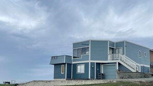 Une maison moderne à deux étages, avec une façade bleue, un garage à l’avant et un escalier menant au deuxième étage.