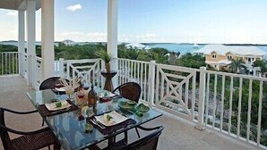 Un espacio comedor al aire libre con techo, con una mesa dispuesta para cuatro personas, con vistas a un paisaje costero.