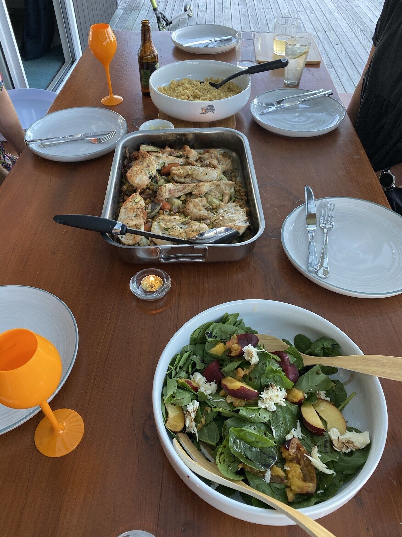 Una mesa de comedor con un plato de pollo asado, una ensalada y varios platos y cubiertos.