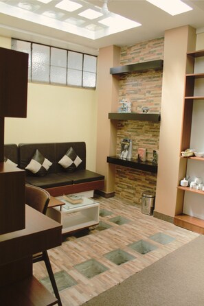 A cozy living area with a sofa, a coffee table, and a bookshelf. - Kaaro Hotel Puno (Puno)