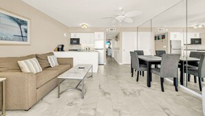 A modern living room with a sofa, coffee table, and dining area with chairs and a table.