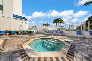 A pool area with lounge chairs, a hot tub, and a palm tree. - Apollo Marco Island - Pool, Hot Tub, Balcony & Directly on the Beach (Marco Island)